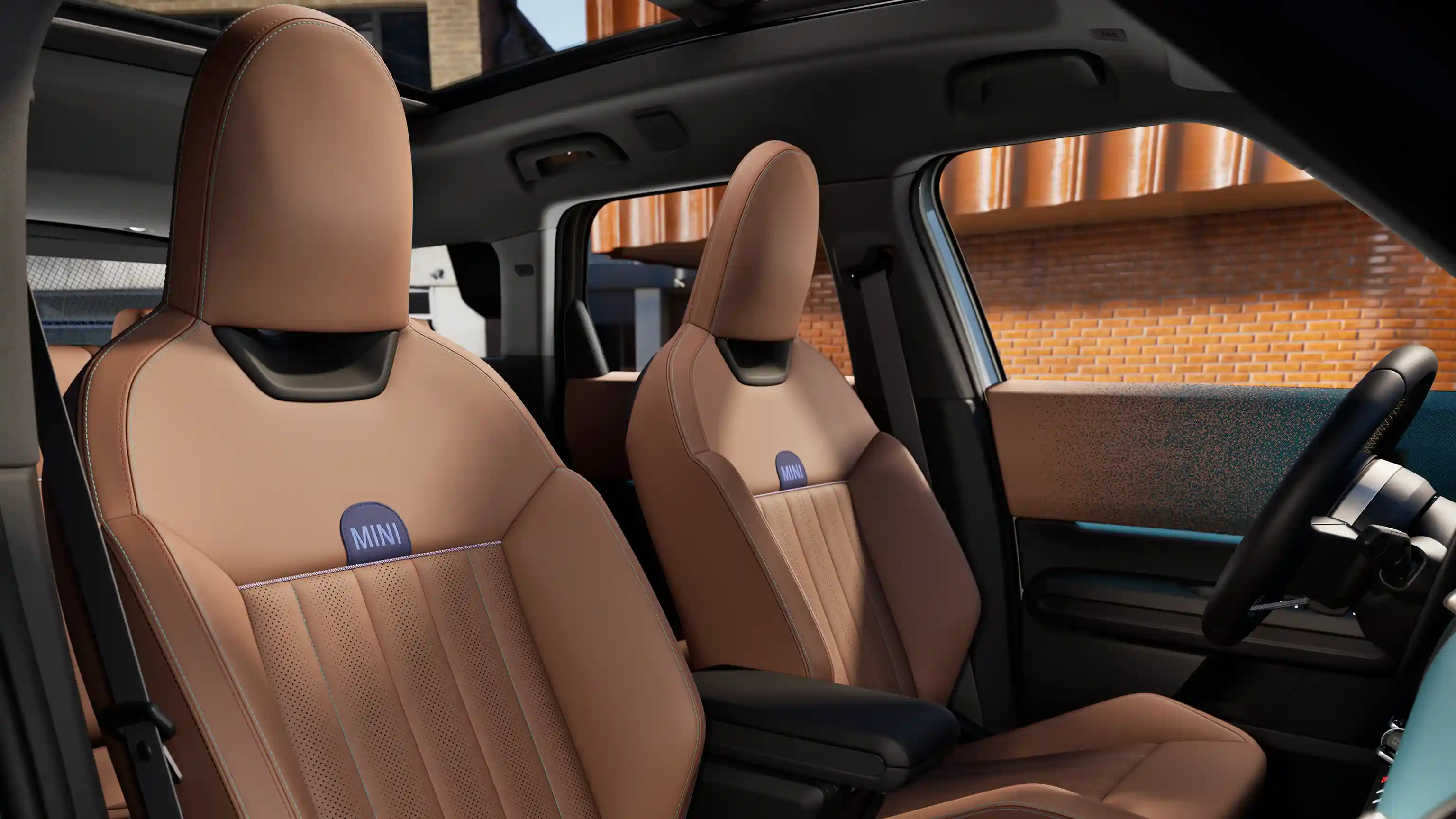 Interior perspective of the MINI Countryman is showing the dashboard, steering wheel, round display, panorama glassroof and back of the frontseats.